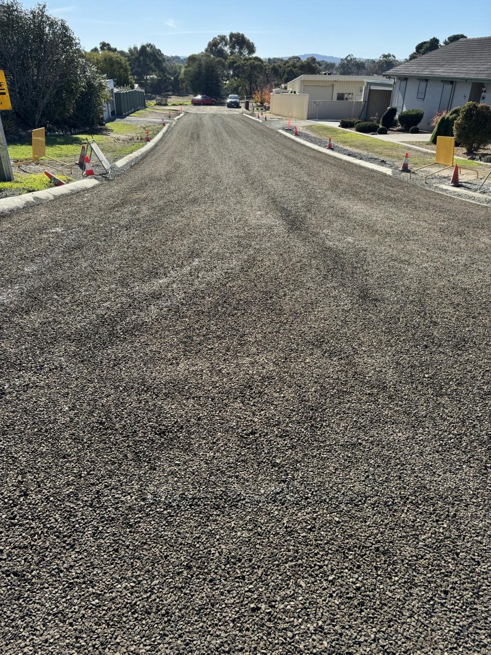 Long shot of a newly-sealed rural road, with trees alongside the roadway's edge