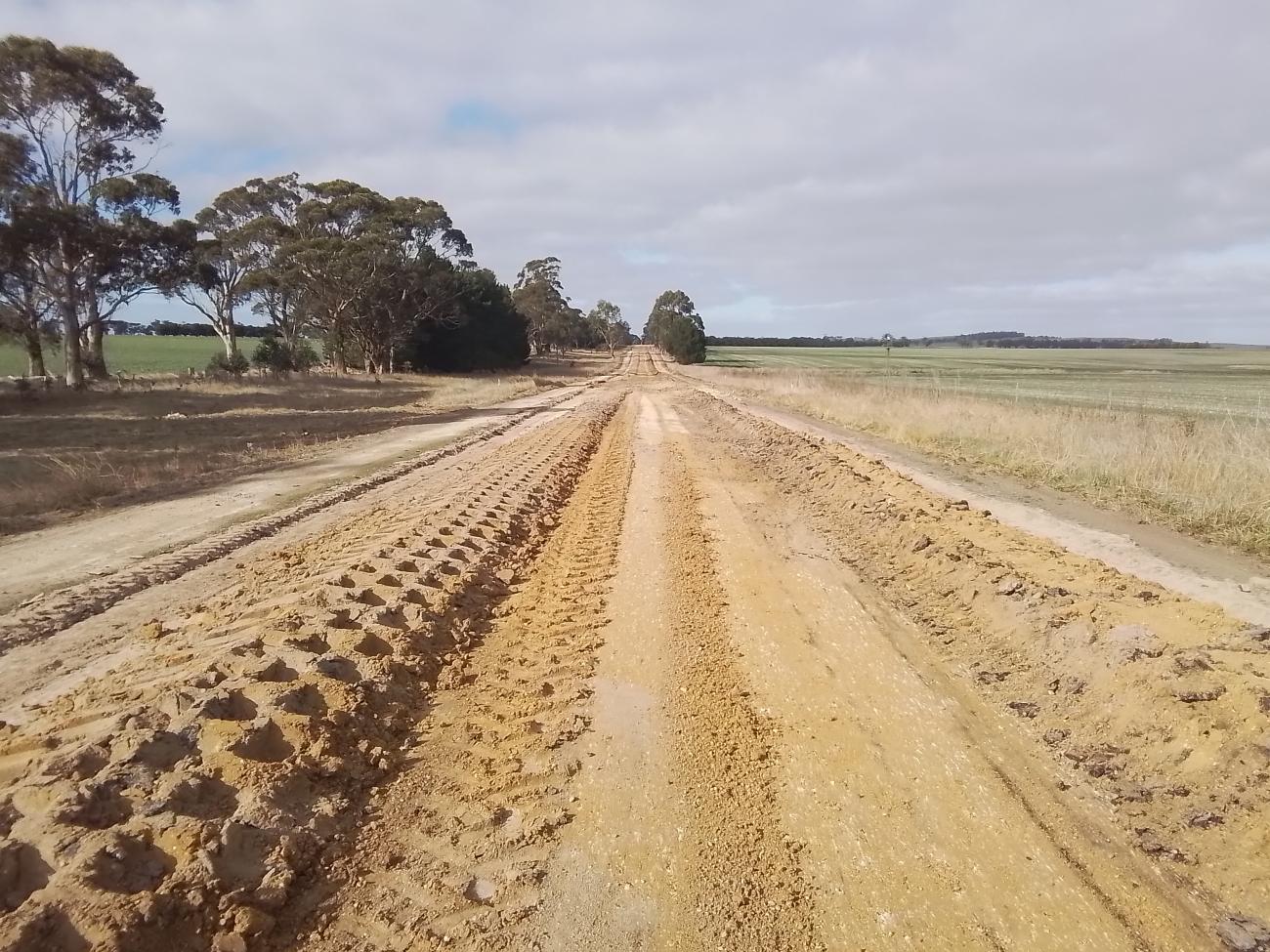 A long rural road whose soil has been prepped for a new surface