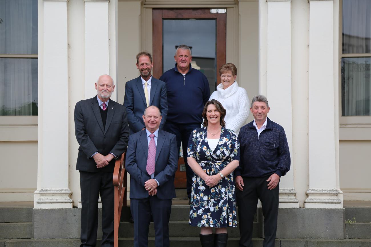 Seven people standing on the steps of a building and smiling for camera