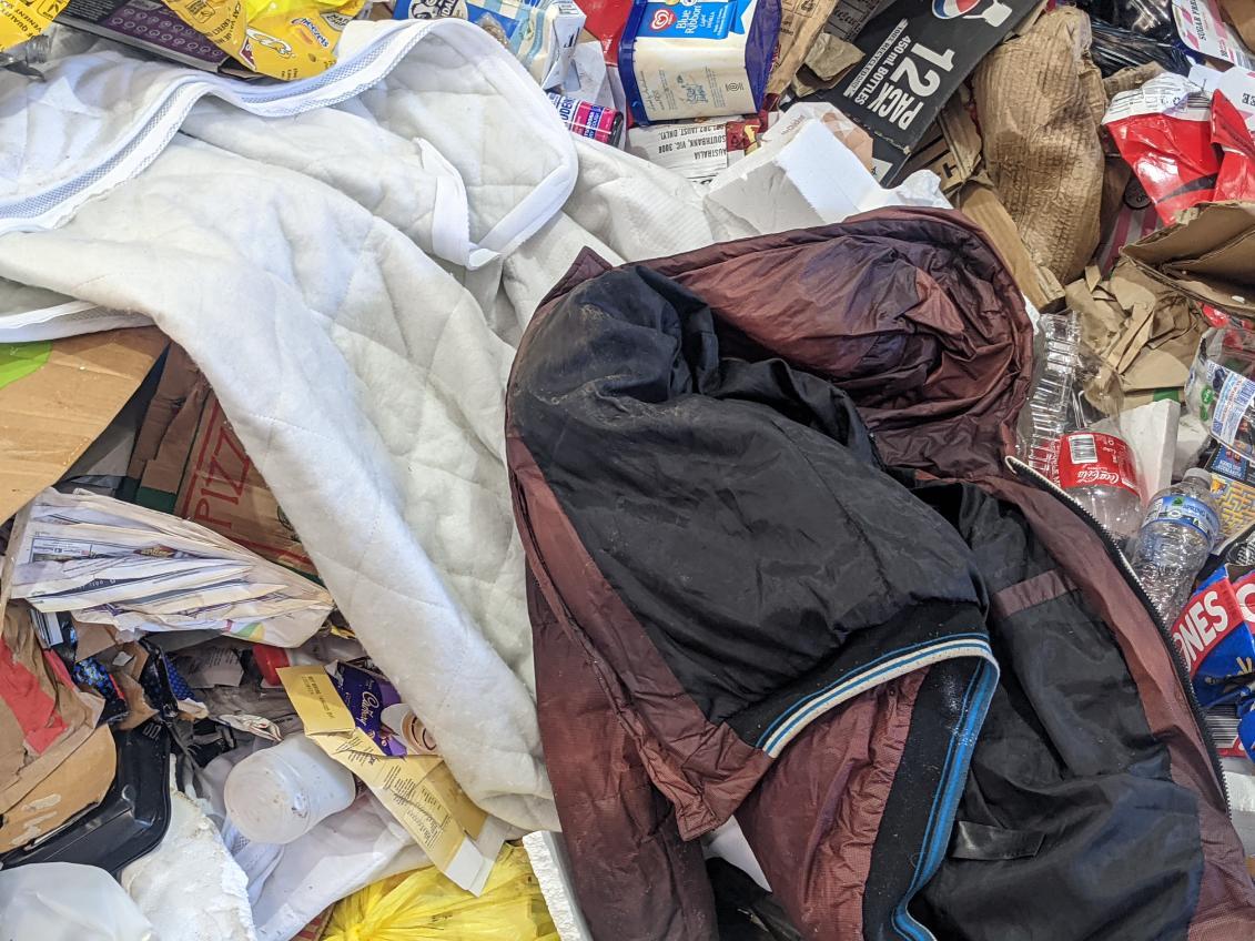 Pile of recycling material mixed with contaminants including bedding and other unrecyclable materials