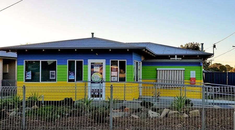 A house painted in bright yellow, blue and green horizontal stripes