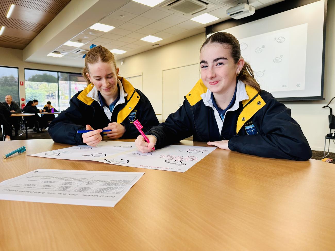 Group of students smiling sitting at a desk