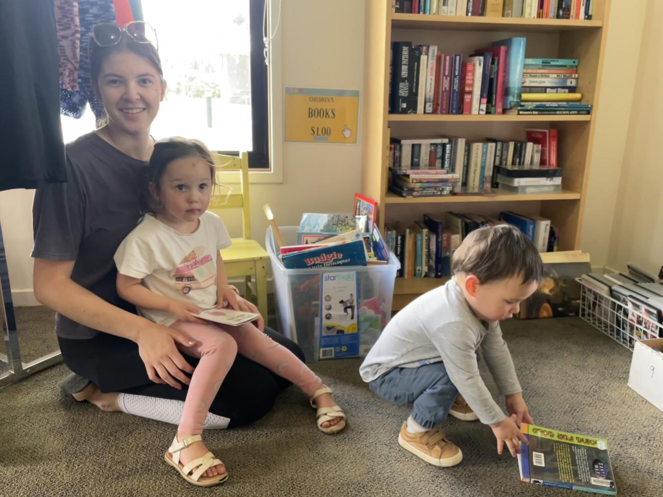 A young woman reading a book to a child, both smiling