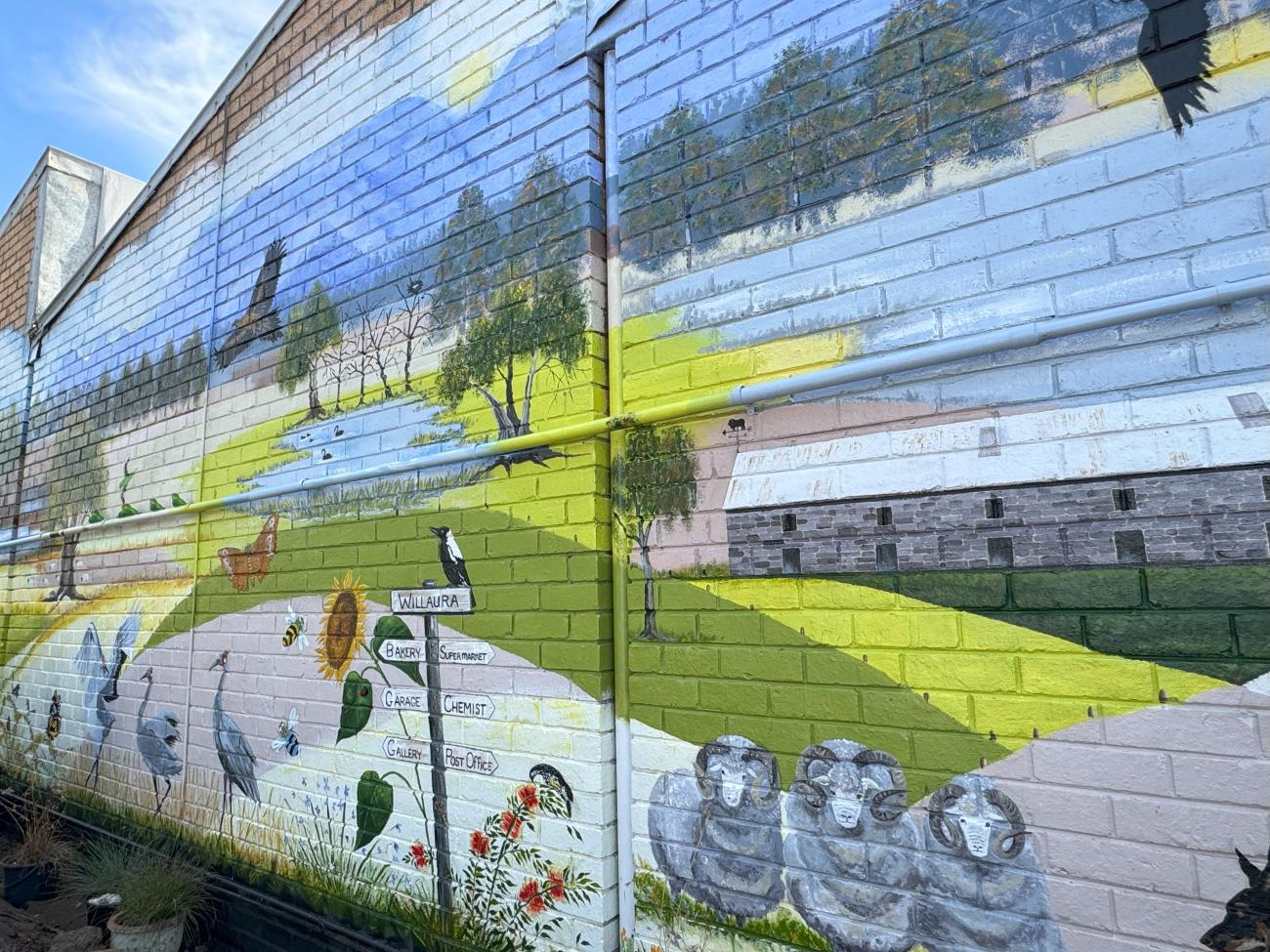 A mural of wildlife and landscape, painted on a large brick wall