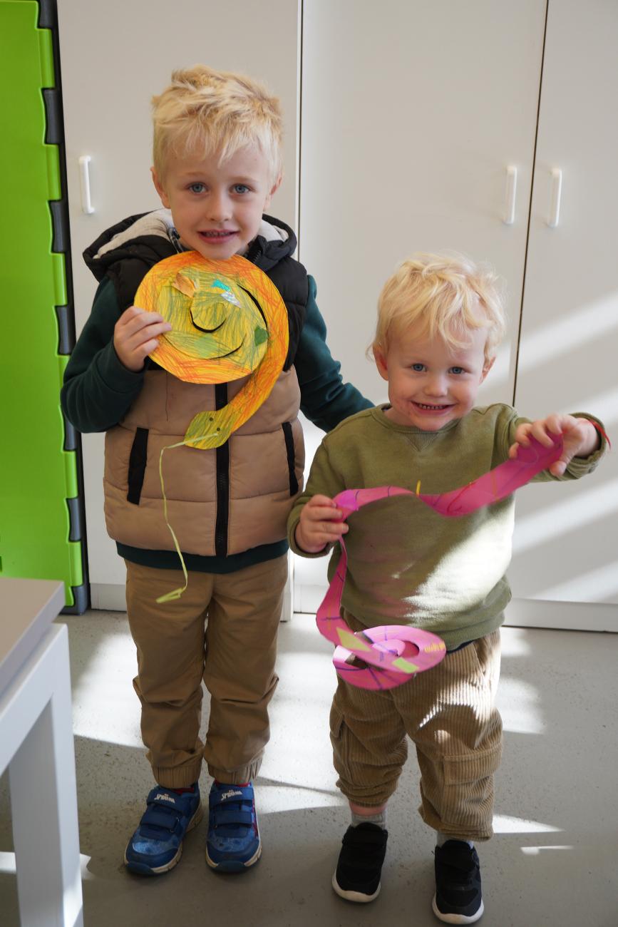 Two children smiling and holding up their artworks