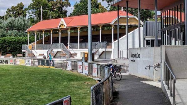 The edge of a suburban football oval with bleacher stands and a pavilion