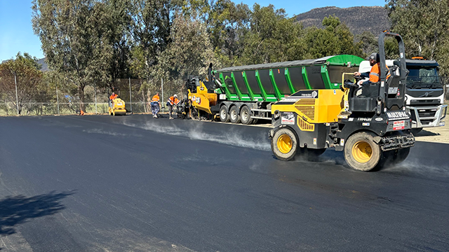 Large construction vehicle resealing tennis court